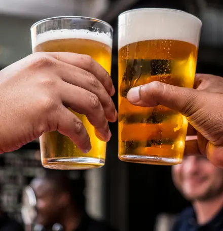 Two beers raised across a table